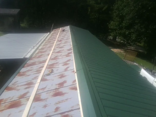 Old rusted panels beside newly installed green metal roofing — Wind Damage Roof Repair by Roofing Brothers in Nevada