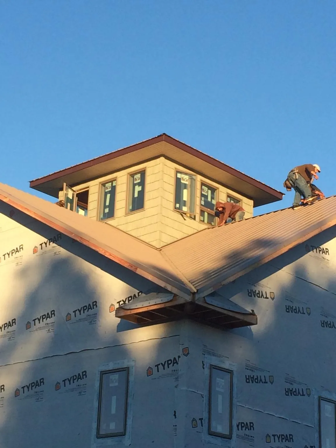 Roofers working around a rooftop cupola on a new metal roof at sunset — Roof Waterproofing in Nevada by Roofing Brothers